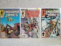 Photo showing three Indiana Jones comic books: The Further Adventures of Indiana Jones #13, Indiana Jones #16, The Further Adventures of Indiana Jones #18 all in good condition lying flat on a carpeted floor.