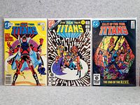 Photo of three vintage DC Comics laid out flat on a surface showing front covers: The New Teen Titans #6, The New Teen Titans #5, and Tales of the New Teen Titans #5.