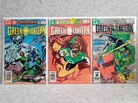 Photo showing three vintage Green Lantern comic books laid flat side by side on a white surface.