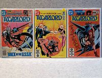 Photo of three comic books from The Warlord series laid flat on a white surface, showing their colorful covers with prominent DC Comics logos and the title 'The Warlord'