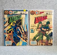 Pair of ATTACK comic books in protective plastic covers displayed side by side on a neutral surface.