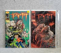 Photo of two PITT comic books, issues #2 and #5, side by side on neutral background, both in plastic protective sleeves.