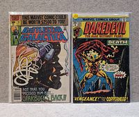 Photo of two vintage comics, Battlestar Galactica #19 and Daredevil #125, both with colorful and detailed covers.