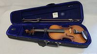 Violin and bow inside open hard shell case lined in blue velvet