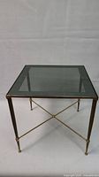 Front view of square side table showing brass frame and glass top