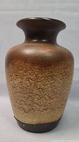 Front view of the textured brown and dark glazed ceramic vase showing shape and glaze details