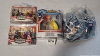 Photo showing two Marvel Super Hero Squad packages, each with two action figures; a Pokemon Zygarde Core figure with Pokeball; and multiple Playmobil toys in sealed bags.