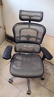 Front view of ergonomic office chair showing mesh back, seat, headrest, and armrests.