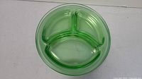 Close-up of one uranium glass divided plate showing three compartments and green translucent glass.