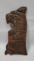 Front view of carved wooden Native American Thunderbird totem pole wall hanging showing intricate facial and geometric design details.