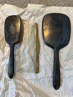 Overview photo of antique vanity set: mirror, brush, and comb laid out on paper