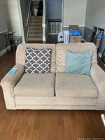 Front view of the beige loveseat showing seat cushions and two pillows.