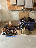 Wide view of lot showing bins and bags filled with floral picks and Halloween decoration pieces including striped witch legs and berry stems