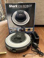 Shark Ion Robot RV720 robot vacuum cleaner with charging dock, power adapter, and product box visible, showing front and top side.