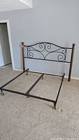 Queen size headboard with dark wood posts and black metal scroll design, viewed from front and side angles.