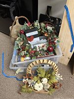 Plastic bin with two wooden baskets; one decorated with white pumpkins and the other partially visible with faux leaves and red berries
