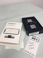 Photo showing the KardiaMobile 6L device in its box alongside the original box and documentation on a light surface.