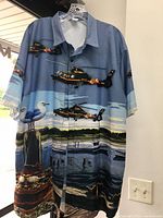 Blue short sleeve button-up shirt hanging, showing Maryland State Police helicopter and waterfront print with boats and seagulls.