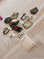 Photo showing a collection of various buckles including metal and plastic styles, with some tagged and in small plastic bags.