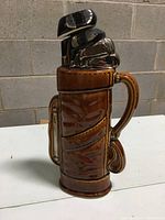 Front view of the brown ceramic golf bag decanter showing golf clubs motif and handle with surface details