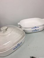 Three-piece CorningWare Blue Cornflower set includes a 10-inch casserole dish with a glass lid and two 9.5-inch dishes without lids, all white ceramic with blue floral pattern.