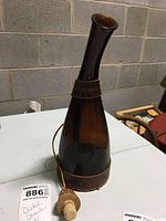 Tall brown glass liquor decanter with narrow neck and leather bands embossed with 'Dickel Tennessee'. Original cork stopper attached by string placed beside the decanter.