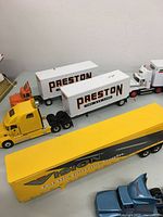 Photo showing yellow Vision trailer and white trailers with Preston branding along with yellow semi truck cab.