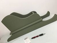 Side view of green wooden decorative sled showing profile and curved runners
