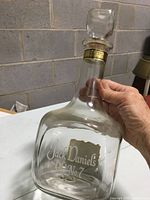 Clear glass Jack Daniel's Old No. 7 decanter held upright showing front logo and gold neck label with glass stopper.