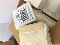 Photo of a bundle of white paper napkins in a box with black printed text and graphics for promotional use by Jack Daniel's and others.