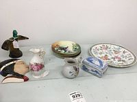 Overview of all 10 decorative items including plates, vase, creamer, ceramic box, wall plaque, and bird-shaped bottle.