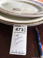 Stacked view of oval ceramic serving platters with visible decorative rims and signs of use.