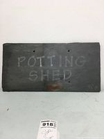 Straight frontal view of the slate sign with faded 'POTTING SHED' text and two mounting holes visible.
