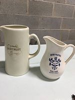 Both whiskey pitchers displayed side by side showing relative sizes and handle shapes.