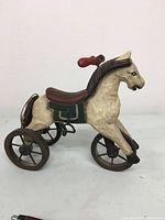Full side view of the wooden horse tricycle toy, showing colors and design.
