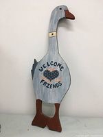Front view of the wooden goose wall plaque showing hand-painted welcome friends text and heart design. Shows size and colors of the plaque.