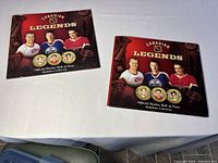 Two Canadian Legends albums on table, one filled with medallions, one empty.