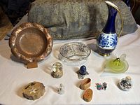 Overview of all collectible items including German cobalt vase, copper plate, glass bowl, worry dolls, stone eggs and figurines.