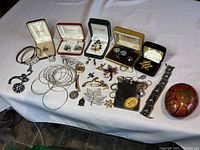 Wide view showing all jewelry pieces including bracelets, earrings, brooches, and the lacquered box on a white cloth