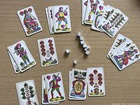 Spread of multiple colorful vintage Pegasus playing cards and seven white dice with black pips on a wooden table.