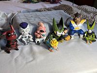 Photo of all 8 figures on fabric surface, showing side angle of each character including Pikachu and Dragon Ball Z figures.