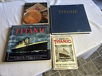 Four Titanic books laid on a round table showing various cover designs and conditions.