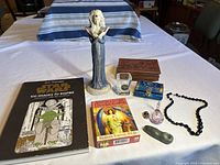 Overview photo of the entire lot showing the Star Wars Art Therapy book, the Mystical Enchantress figure, the Archangel Oracle Card deck, trinket boxes, necklace, glass items, and stone pipe.