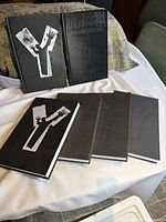 Six hardcover graphic novels arranged on table, five lying flat, two standing upright