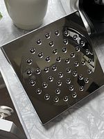 Top view of square shower head face with 36 nozzles in circle pattern