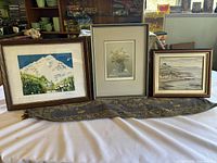 Photo showing all three framed art pieces side by side on a surface with a decorative runner beneath.