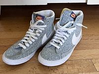 Pair of Nike Blazer limited edition women's sneakers showing leaf pattern fabric upper, white swoosh and laces, gum sole.