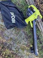 Full leaf vacuum and mulcher unit with collection bag lying on the ground.