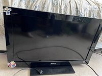 Front view of the 32 inch Sony Bravia LCD TV showing intact screen and black bezel frame with power cord attached.