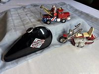 Photo showing all three items: red and cream Tonka die cast motorcycle, red and blue Corgi Berliet tow truck, and black Harley Davidson pen case with logo.